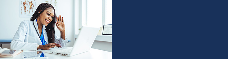 Smiling female doctor waving during a video call on her laptop.