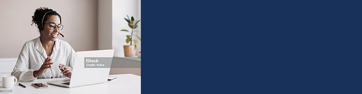 Woman wearing earbuds taking notes while looking at a laptop at a table.